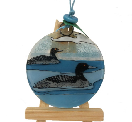 Two loons on a blue background glass ornament